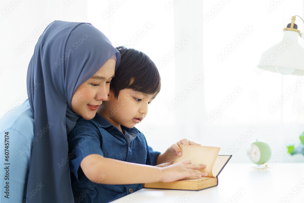 Happy cheerful Asian muslim woman woman teaching her little son a drawing on digital tablet. Happy cheerful Asian muslim woman woman teaching her little son a drawing on digital tablet.