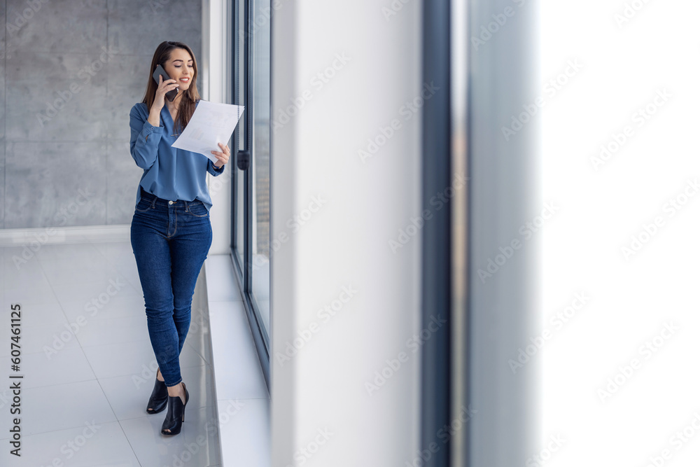 Smiling businesswoman standing in modern office with smartphone