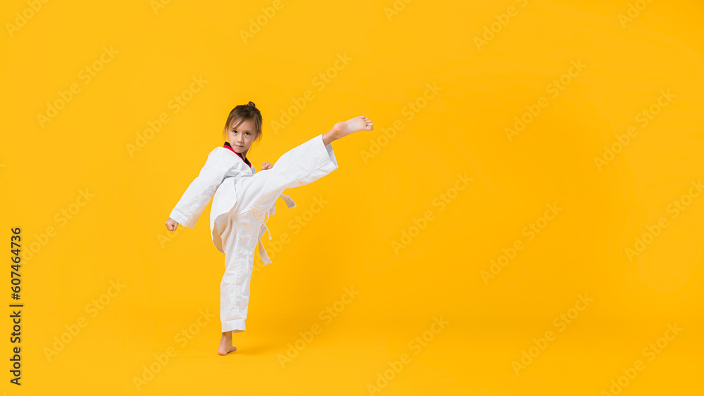 Banner: Asian-Australian girl poses in martial arts Practice taekwondo, karate, judo against a yellow background in the studio. Asian kids karate or Taekwondo martial arts. Sport kid training action. - obrazy, fototapety, plakaty 