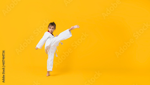 Banner  Asian-Australian girl poses in martial arts Practice taekwondo  karate  judo against a yellow background in the studio. Asian kids karate or Taekwondo martial arts. Sport kid training action.