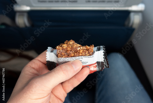 White male holding and eating an airplane snack while seated