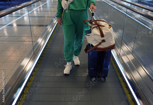Young woman standing with luggage on a moving walkway at an airport