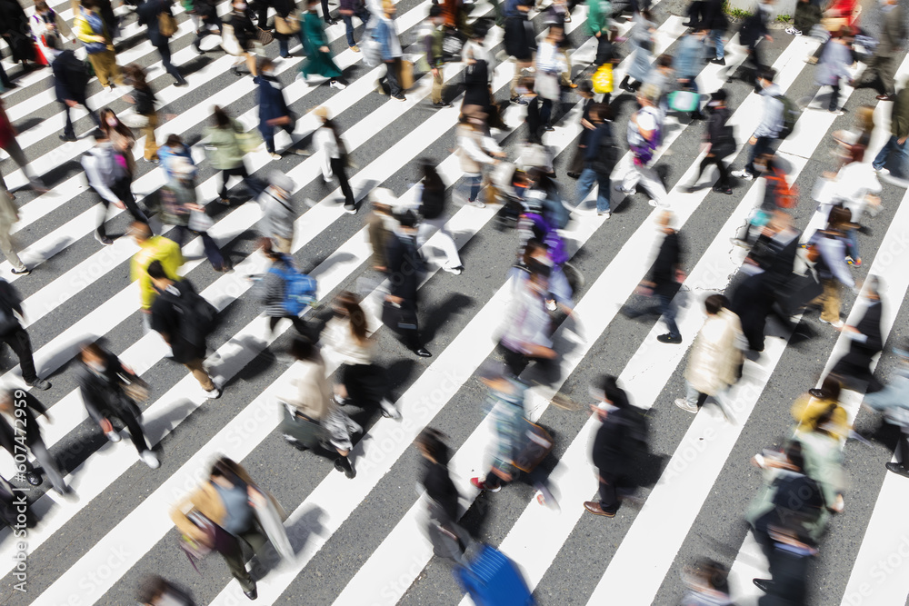 Obraz premium picture with intentional motion blur of crowds of people crossing a city street in Tokyo, Japan