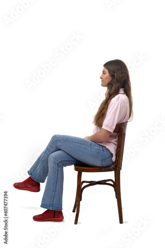 Side view of a young girl sitting on chair with cross legged on white background