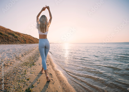 a woman in a tracksuit walks near the sea on the beach photo