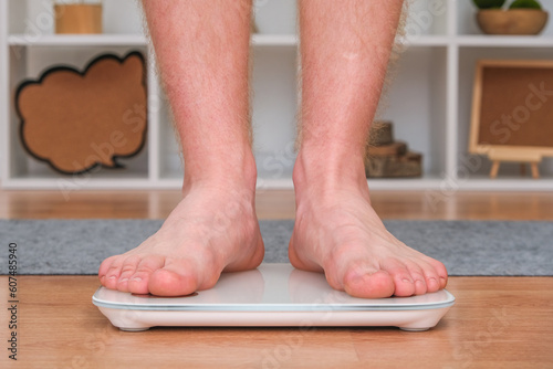 A man stands on the scales. The guy is weighing himself. Floor scales for health. Weight control.