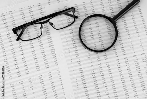 Magnifying glass and eye glasses on financial documents.