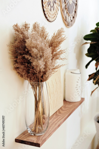 side view of pampas grass bouquet in transparent glass vase on a shelf. trendy modern interior design