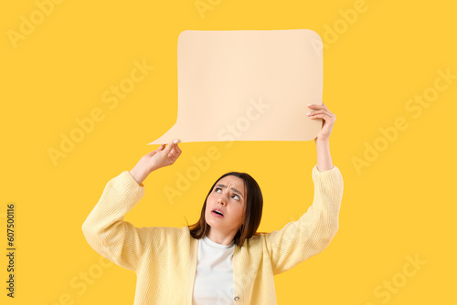 Upset young woman with blank speech bubble on yellow background