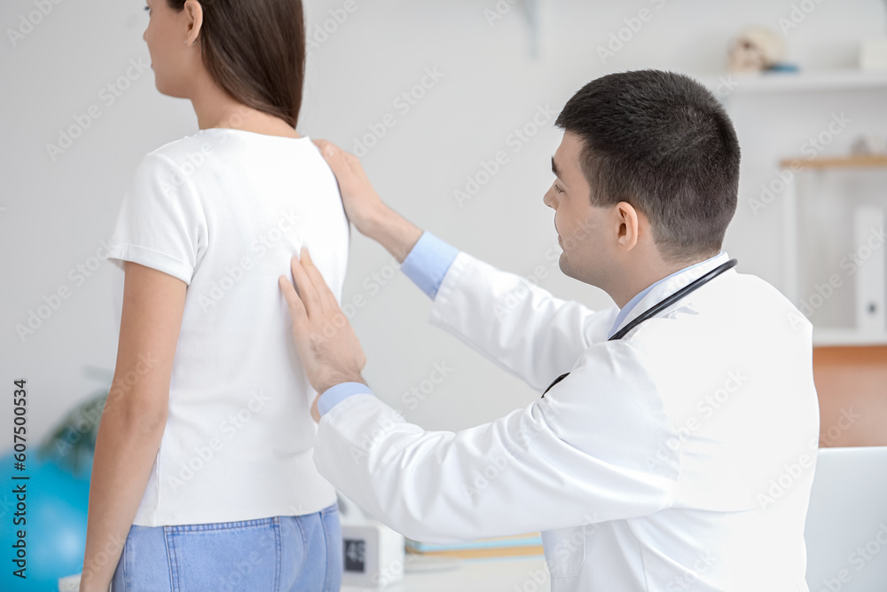 Male doctor checking posture of young woman in clinic Male doctor checking posture of young woman in clinic