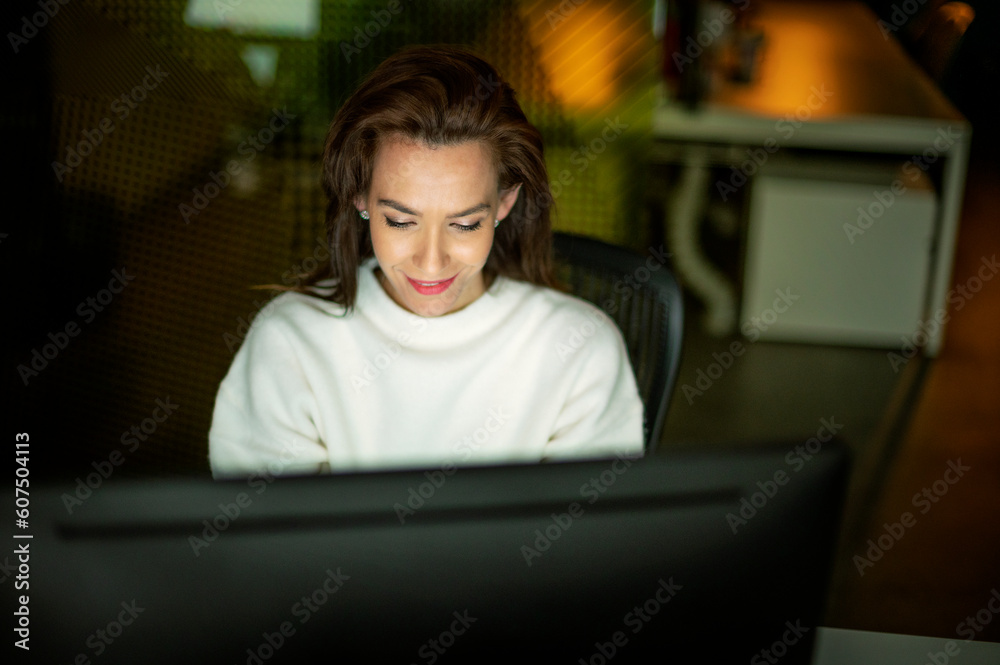 Mid aged businesswoman using computer in late evening at the office