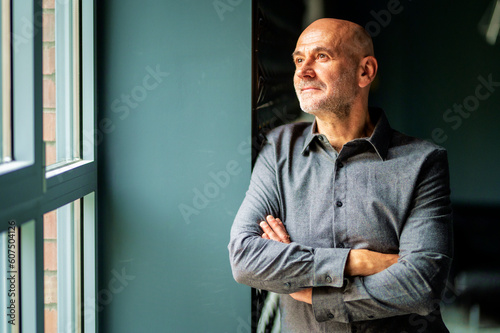 фотографія Portrait of thinking business man standing with arms crossed at the office