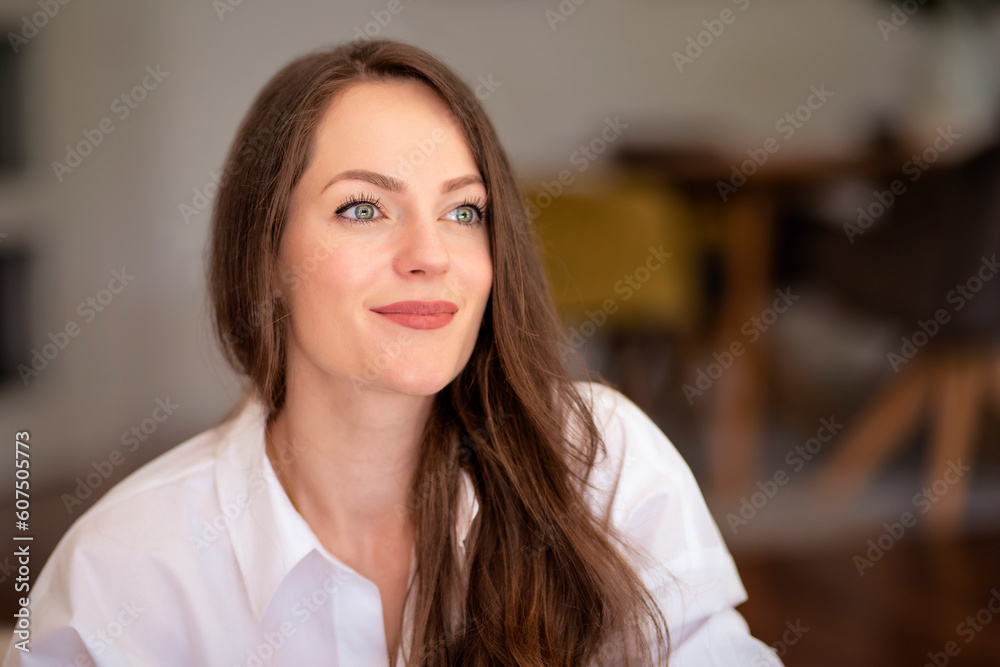 Portrait of brunette haired young woman looking thoughtfully and relaxing in an armchair at home