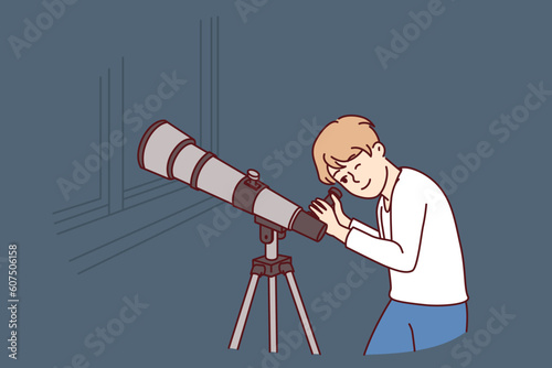 Teenager boy with telescope watches stars and is fond astrology while standing in apartment near window. Child uses telescope wishing to visit space and become astronaut from scientific expeditions