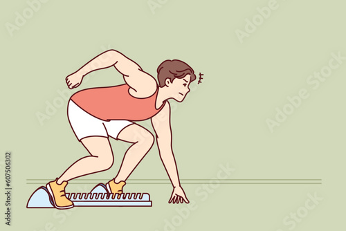 Man sprinter prepares for race standing in starting position in sports stadium. Sprinter athlete participates in running tournament competing with rivals in speed of overcoming distance