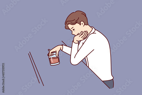 Man drinks alcohol sitting alone in bar and suffers from depression after divorce or being fired from job. Sad guy with glass of whiskey experiences alcohol addiction due to failures in personal life