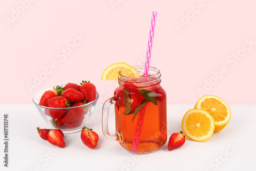 Mason jar of tasty strawberry drink with fresh berries and lemon on white background