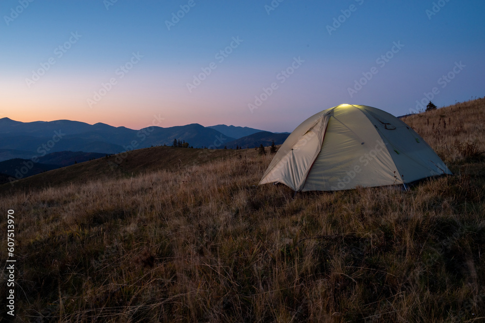 A tourist tent stands on top of a mountain. Camping at the top of the mountain.