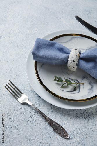 Plates with folded napkin and cutlery on grunge grey background
