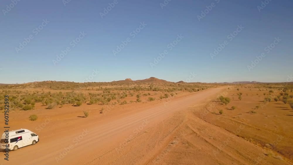 Aerial view of a small camper van driving on a desert road, Ernest Giles Road, Northern Territories, Australia.