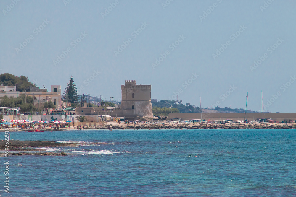 Torre Vado desde la Marina di Salve en un caluroso día de verano, Puglia, Italia. Bañistas tomando el sol o dándose un baño en la conocida como Las Maldivas de Salento.