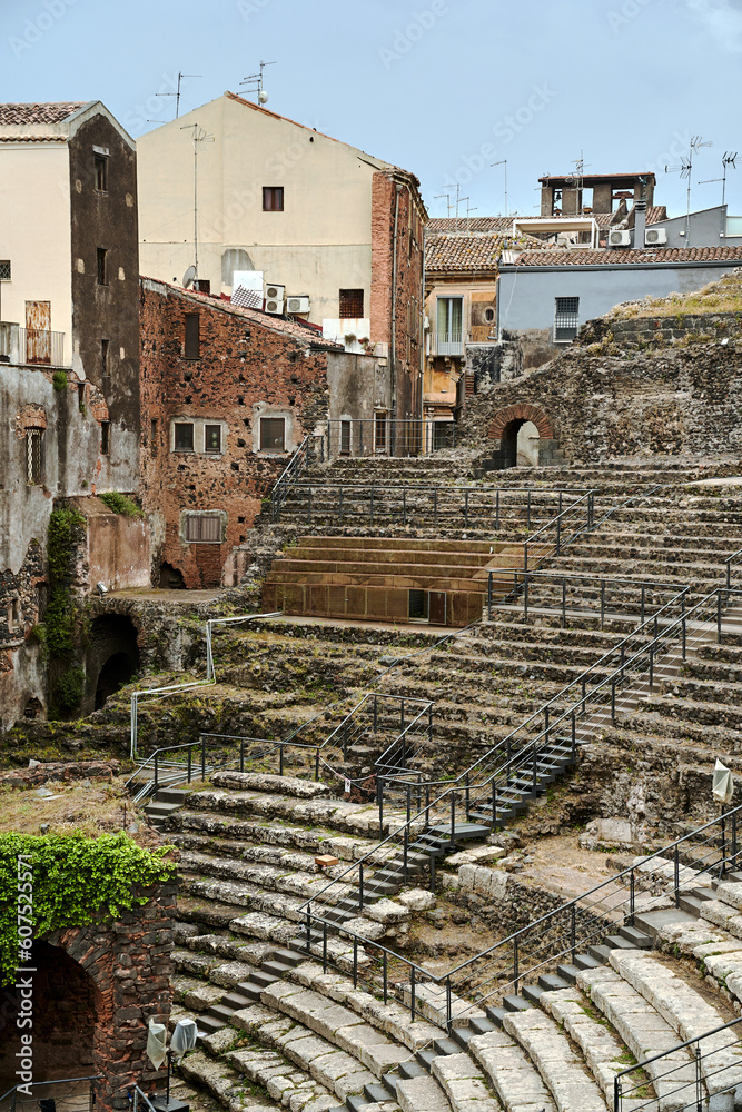 The ruins of an ancient Greek theater and the walls of historic tenement houses in the city of Catania