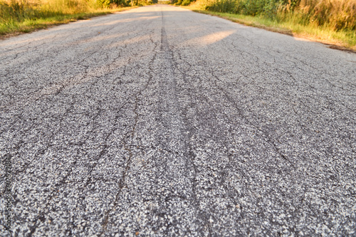 The gray cracked asphalt of the paved road