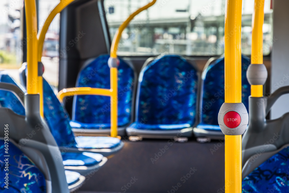 Stop button on the modern public transport bus. Empty bus interior. Public transport in the city. Passenger transportation. Bus with blue seats and yellow handrails. Stop button on the modern public transport bus. Empty bus interior. Public transport in the city. Passenger transportation. Bus with blue seats and yellow handrails.