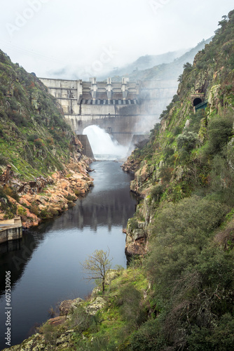 View of the Tua mouth hydroelectric dam in Portugal discharging water on a cloudy autumn day.