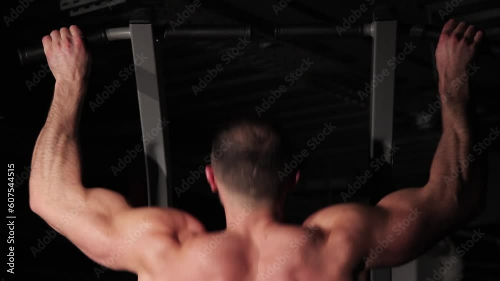 Muscular bodybuilder guy works out his back muscles on the bar Muscular bodybuilder guy works out his back muscles on the bar