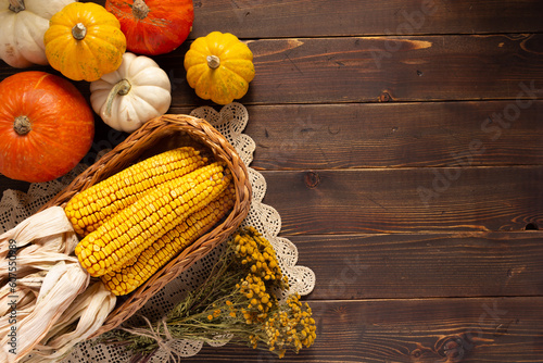 Dried corn cob and pumpkin at wooden table as autumn still life photo