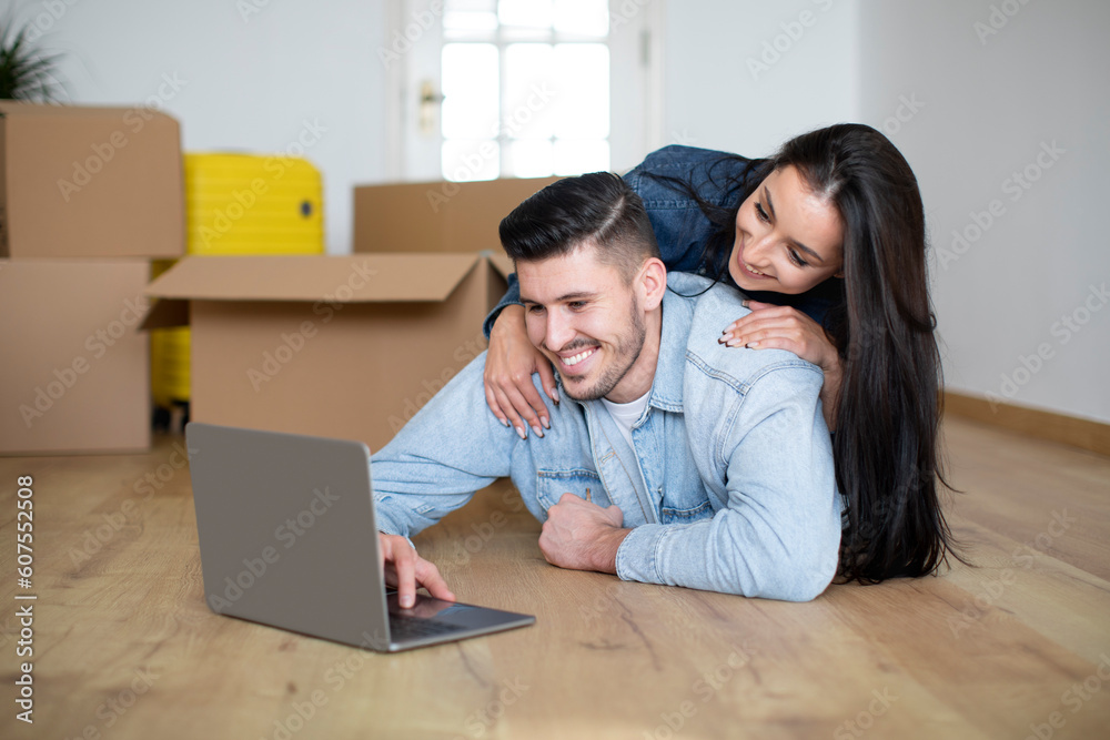 Searching Design Ideas. Happy Couple Using Laptop After Moving In New House Searching Design Ideas. Happy Couple Using Laptop After Moving In New House
