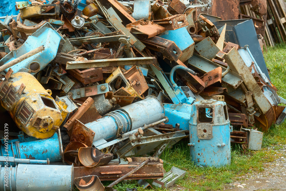 A pile of scrap metal on the grass. A pile of scrap metal from old cars lying in the green grass