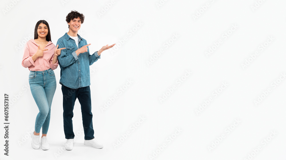 Fototapeta premium Cheerful Couple Showing Copy Space Pointing Fingers Aside, White Background