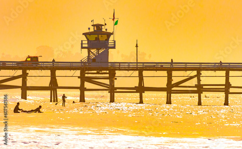 Surfers at San Clemente pier in the golden light of a summer sunset in Southern California