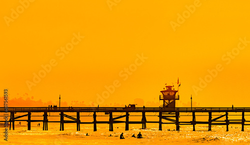 Surfers at San Clemente pier in the golden light of a summer sunset in Southern California photo