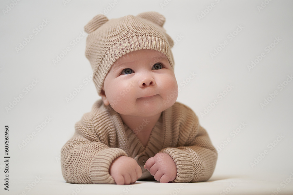 an infant lying on his belly in a beige knitted garment an infant lying on his belly in a beige knitted garment