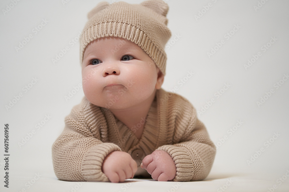 an infant lying on his belly in a beige knitted garment an infant lying on his belly in a beige knitted garment