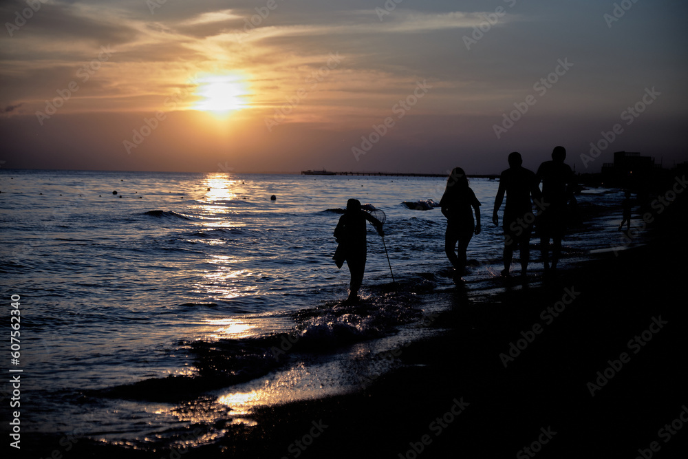 silhouette of a family by the sea at sunset in summer. silhouette of a family by the sea at sunset in summer.