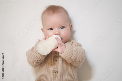 A newborn baby drinks milk from a bottle. Studio photo