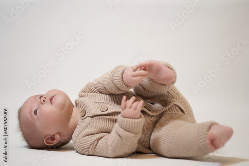 Portrait of a newborn baby on a light background lying on his back with his legs up