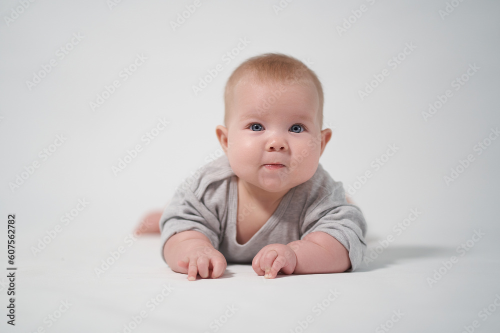 a smiling baby lies on his stomach looking at the operator at the camera. photography on a light background of a newborn baby a smiling baby lies on his stomach looking at the operator at the camera. photography on a light background of a newborn baby