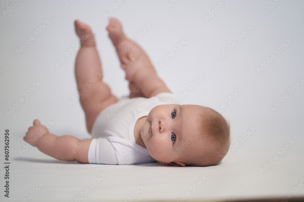 A newborn baby is trying to roll over on his stomach. photography on a light background A newborn baby is trying to roll over on his stomach. photography on a light background