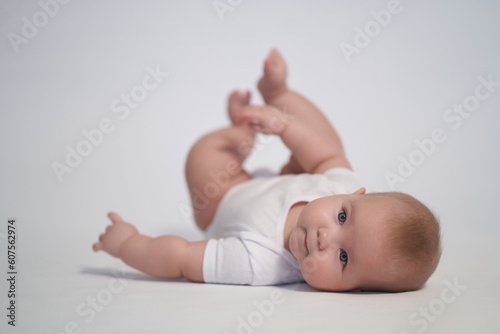 A newborn baby is trying to roll over on his stomach. photography on a light background