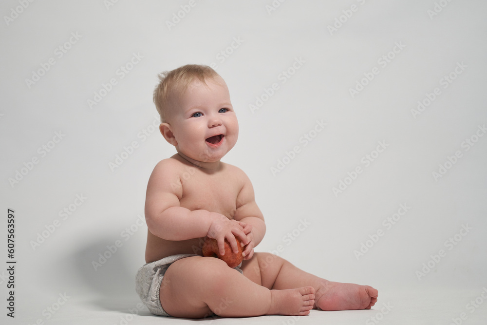 a child of 7 months sitting on the pope smiles holding a red apple in his hands. a child of 7 months sitting on the pope smiles holding a red apple in his hands.