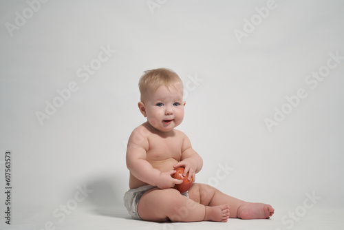 a child of 7 months sitting on the pope holds a red apple in his hands. photography on a light background photo