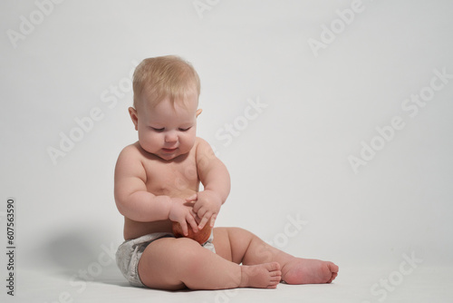 a child of 7 months sitting on the pope holds a red apple in his hands. photography on a light background