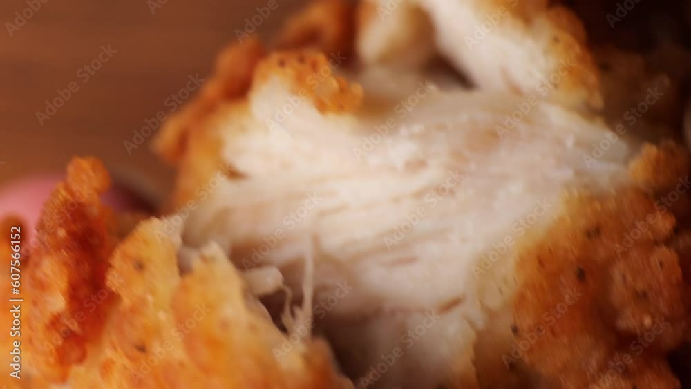 Girl's fingers tearing apart a piece of fried filet chicken nuggets. Macro, chicken nugget fibers