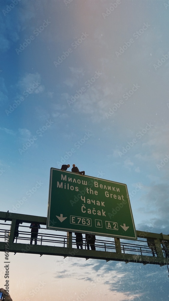 People sitting on a road sign in Serbia 