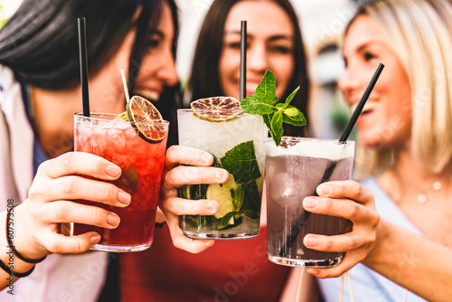 Group of happy friends toasting and drinking fancy cocktails at bar terrace-Three Young girls drink mojito and clinking glass together at pub enjoying happy hour at summer party- Life Style concept 